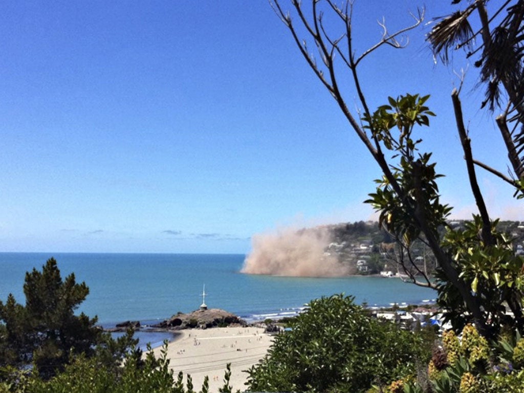 Dust rises from rocks falling from a cliff in the Christchurch suburb of Sumner moments after the earthquake struck