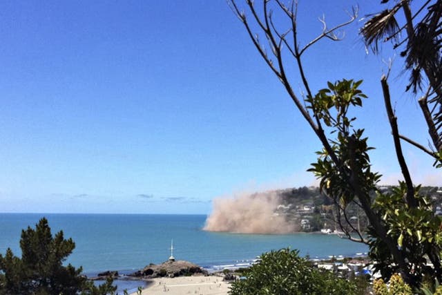 Dust rises from rocks falling from a cliff in the Christchurch suburb of Sumner moments after the earthquake struck