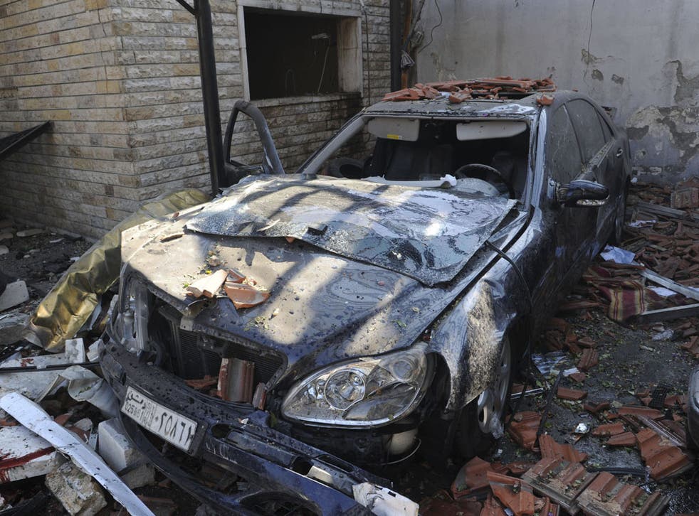 A damaged car is seen where a car bomb blew up at security sites in Damascus