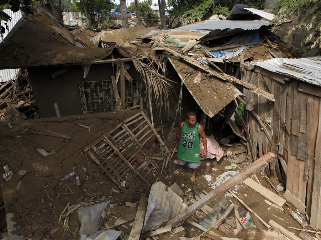 A flood victim stands amid the wreckage of his home in a village
near Iligan yesterday