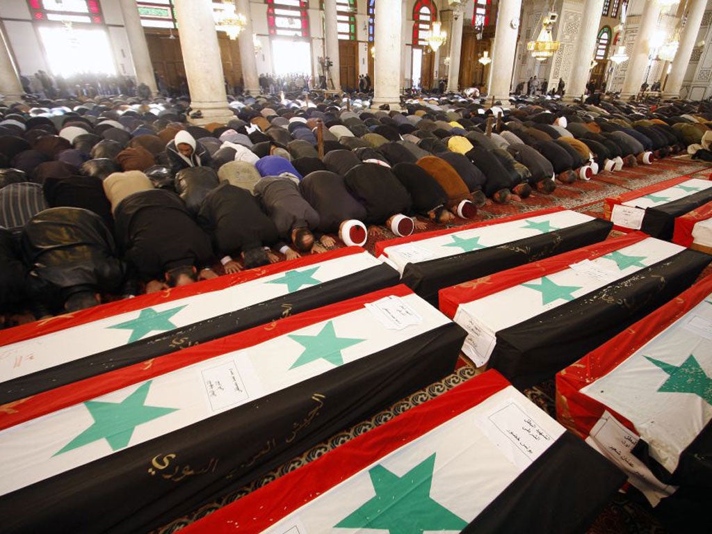 Mourners bow in prayer at a mass funeral for 44 people killed in twin suicide bombings that targeted intelligence agency compounds in Damascus