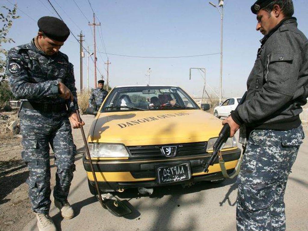 Iraqi policemen check a car at a street in central Baghdad after the latest attacks