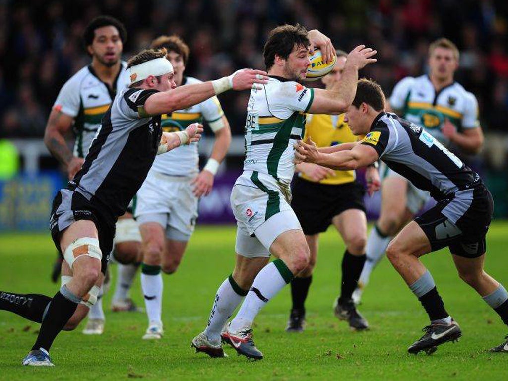 The Northampton and England full-back Foden (centre) - who scored two tries - fends off two Newcastle Falcons challenges