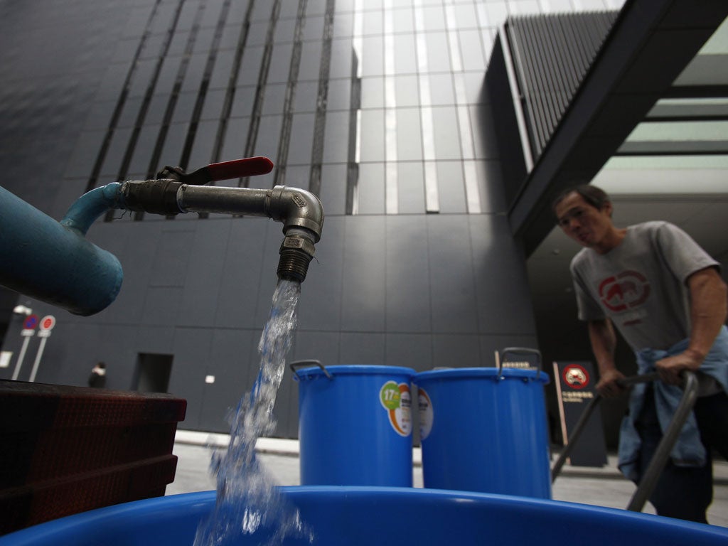 A worker transports buckets of clean water from a water tanker into Hong Kong's new government headquarters