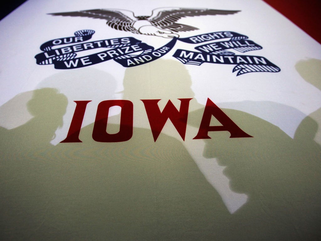 Voters cast shadows on an Iowa state flag at a campaign rally