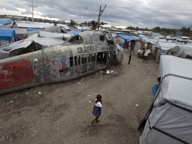 A girl walks past an abandoned helicopter at a camp in Port-au-Prince, which was set up for people displaced by the 2010 earthquake. More than half a million Haitians are still homeless