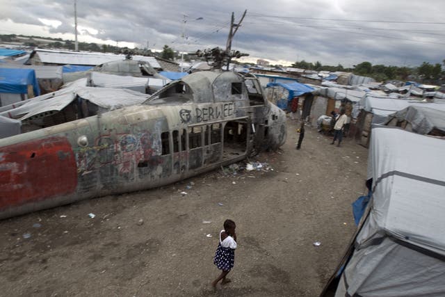 A girl walks past an abandoned helicopter at a camp in Port-au-Prince, which was set up for people displaced by the 2010 earthquake. More than half a million Haitians are still homeless