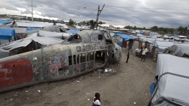 A girl walks past an abandoned helicopter at a camp in Port-au-Prince, which was set up for people displaced by the 2010 earthquake. More than half a million Haitians are still homeless