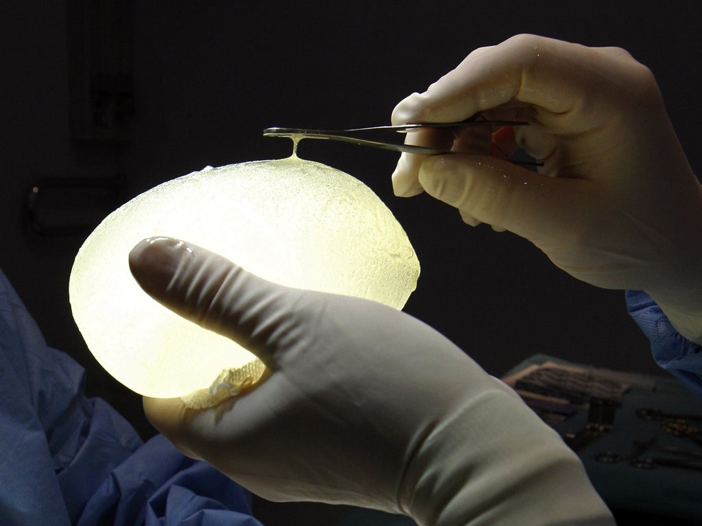 A French plastic surgeon holds one of the defective PIP breast implants removed from a patient a few days before Christmas