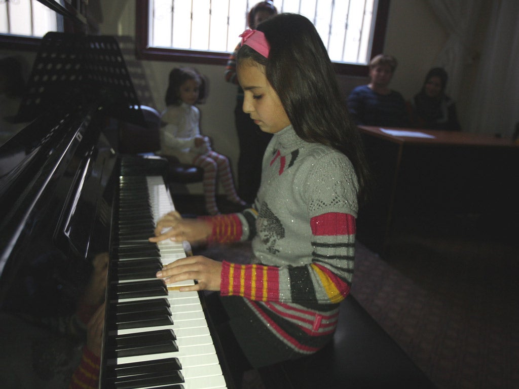 Children hone their skills at the Gaza Music School,
watched by staff