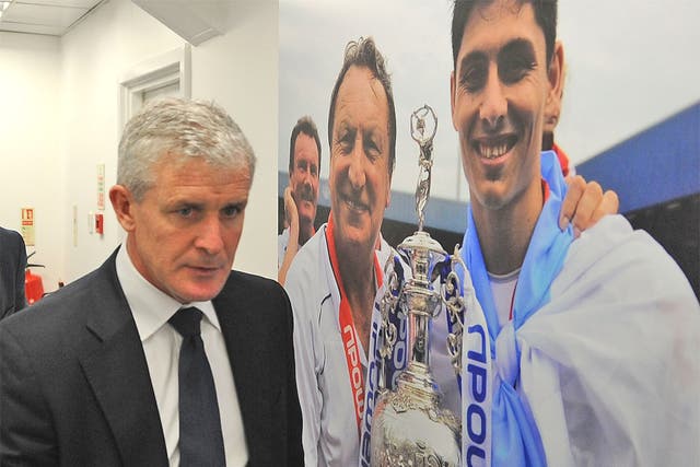 Mark Hughes walks past a picture of his predecessor Neil Warnock at Loftus Road yesterday