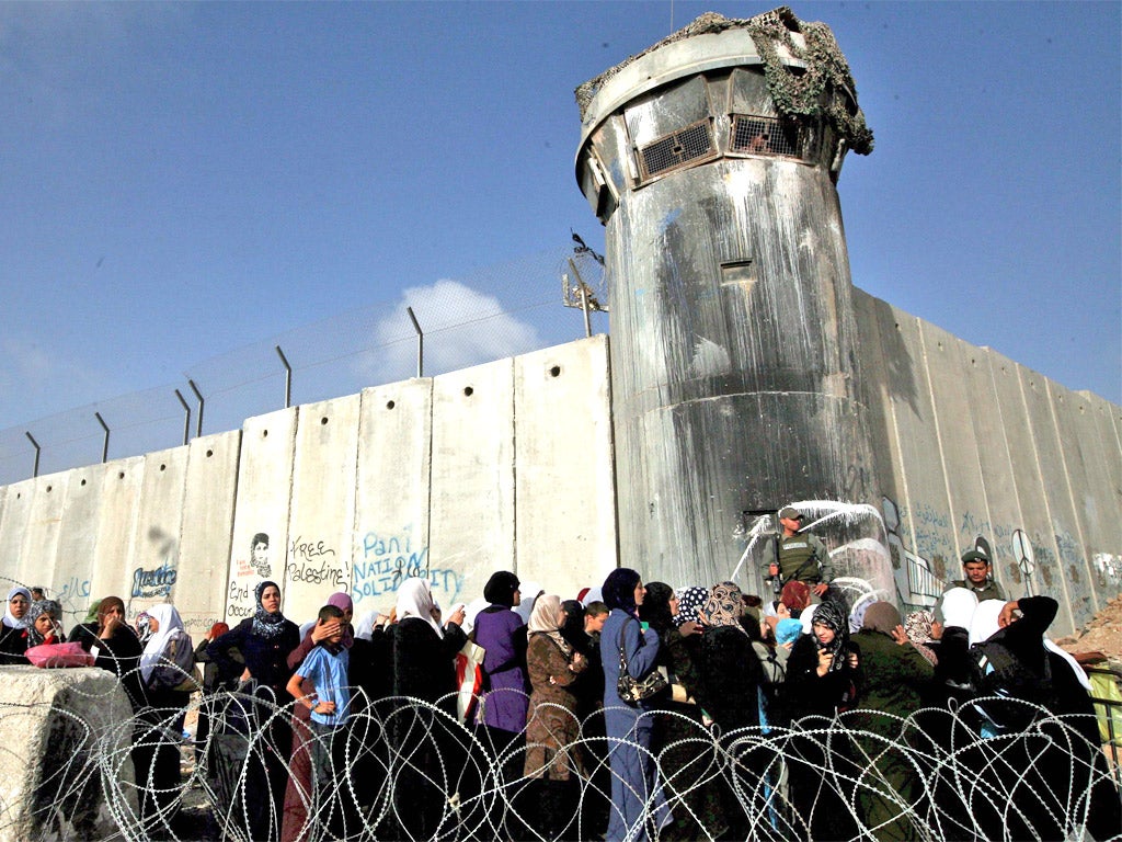 Palestinians wait to pass a checkpoint outside the West Bank city of Ramallah