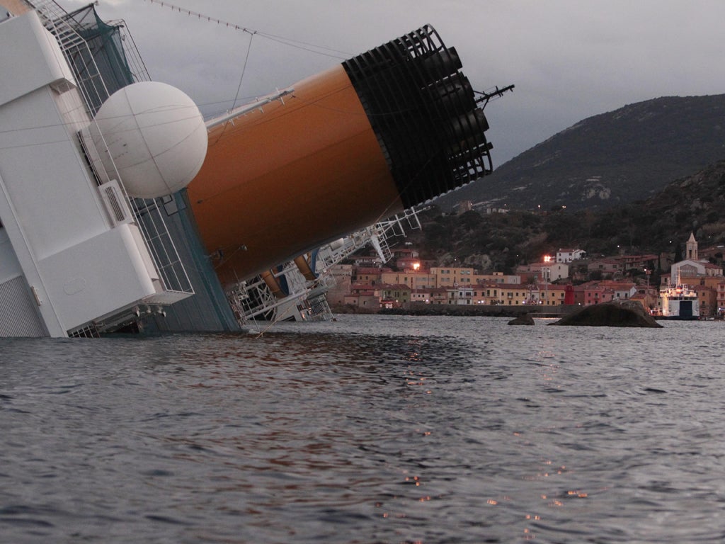 The listing hull of the Costa Concordia looms over Giglio harbour last night