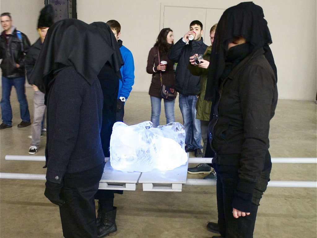 Hooded figures carry the piece of ice on a sledge