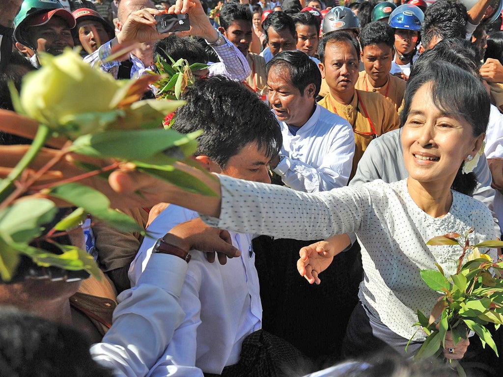 Aung San Suu Kyi is surrounded by supporters as she leaves the Thanlyin township