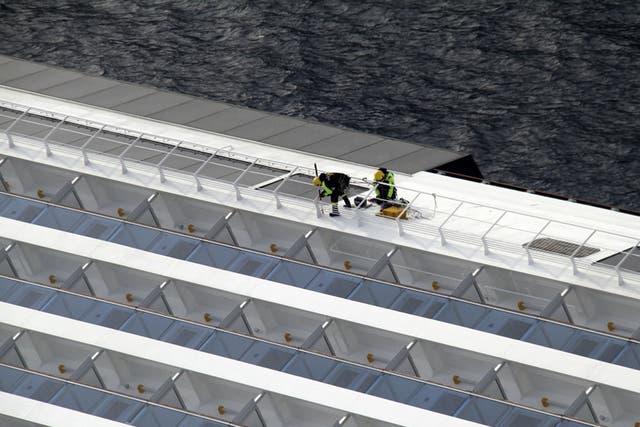 Firefighters work on the side of the Costa Concordia yesterday