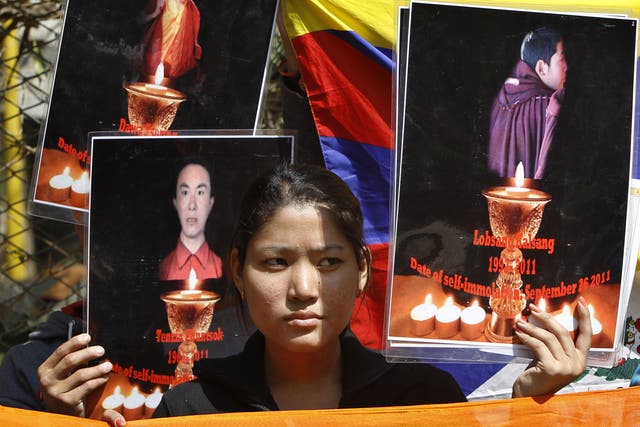 A Tibetan exile holds the photographs of Tibetan monks who have self immolated in Tibet protesting Chinese government, during a demonstration to support three fellow Tibetan exile students 