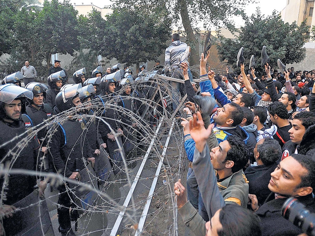 Protesters shout slogans at security forces during a protest outside the interior ministry in Cairo
