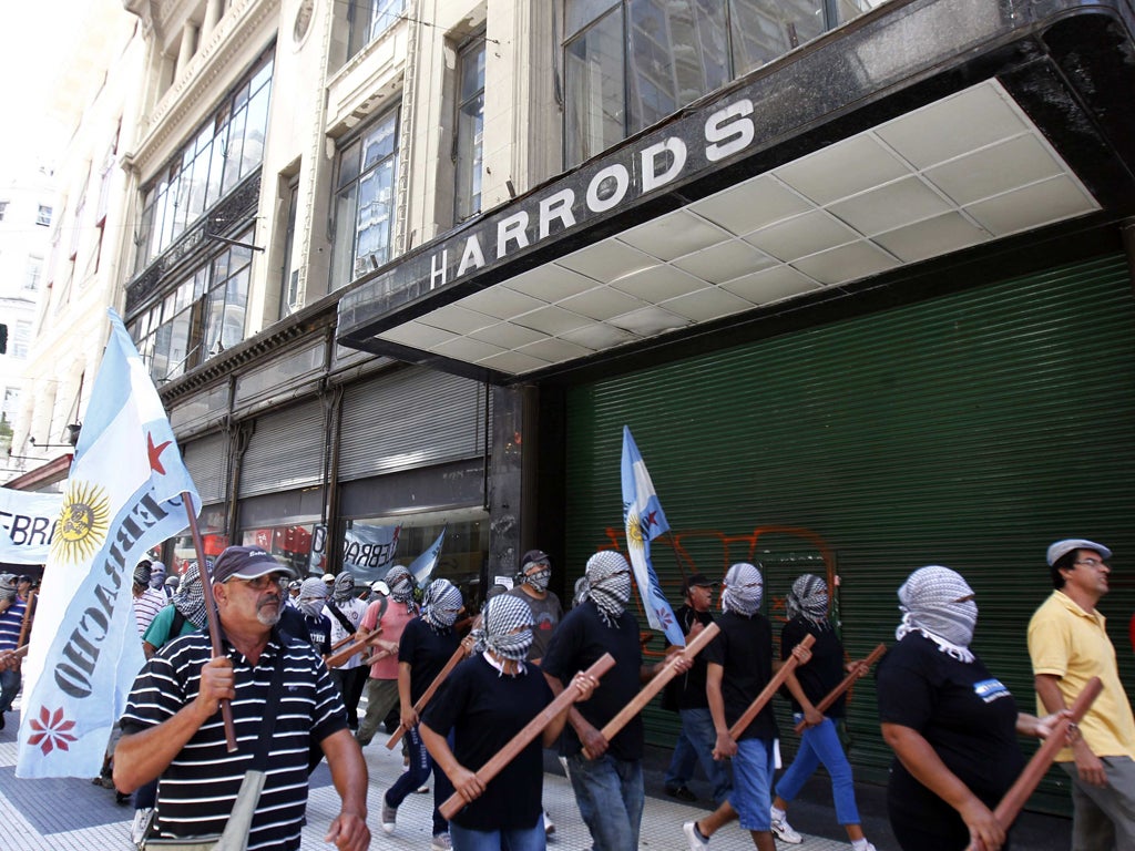 Masked demonstrators march past an abandoned Harrods store in Buenos Aires