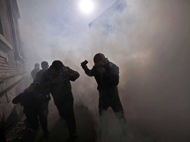 Egyptian protesters react as they get caught by tear gas fired by security forces during clashes near the Interior Ministry in Cairo