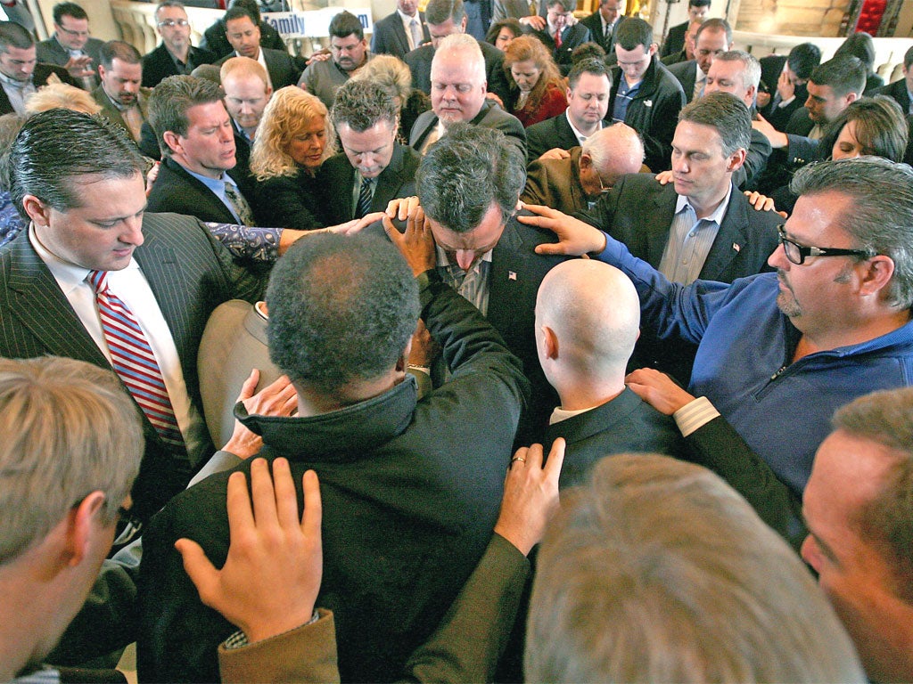 Republican supporters pray over Rick Santorum, centre, during a campaign stop in 2012