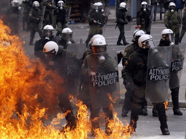 A petrol bomb explodes near riot police during protests in Athens today