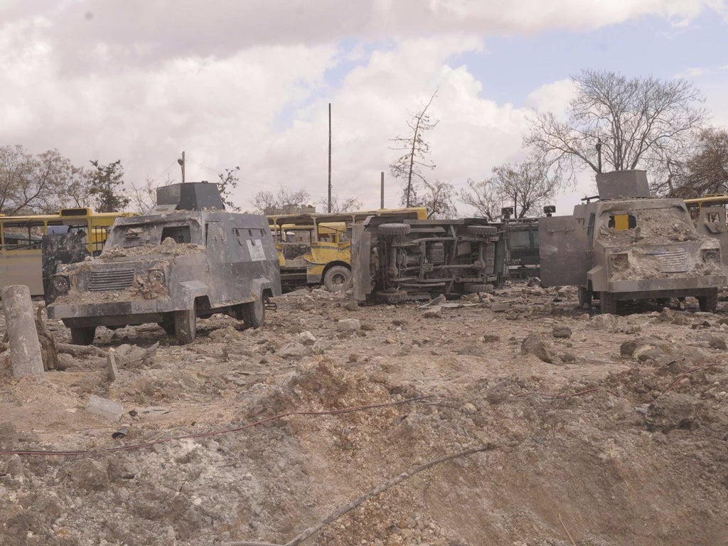 Vehicles damaged and covered in dust are seen outside the police headquarters building, one of two sites of bomb blasts in Syria's northern city of Aleppo