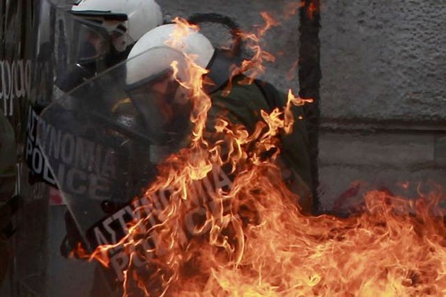 A petrol bomb explodes near riot police during demonstrationsin Athens