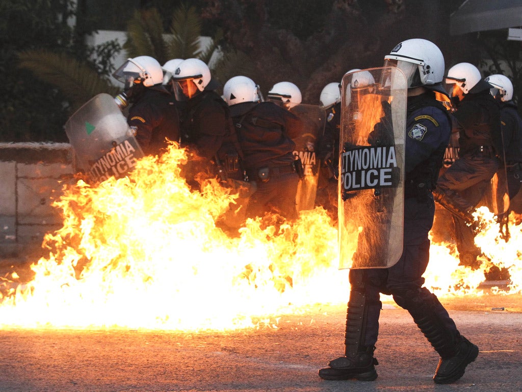 Riot police are attacked by a petrol bomb during anti-cuts protests in Athens yesterday