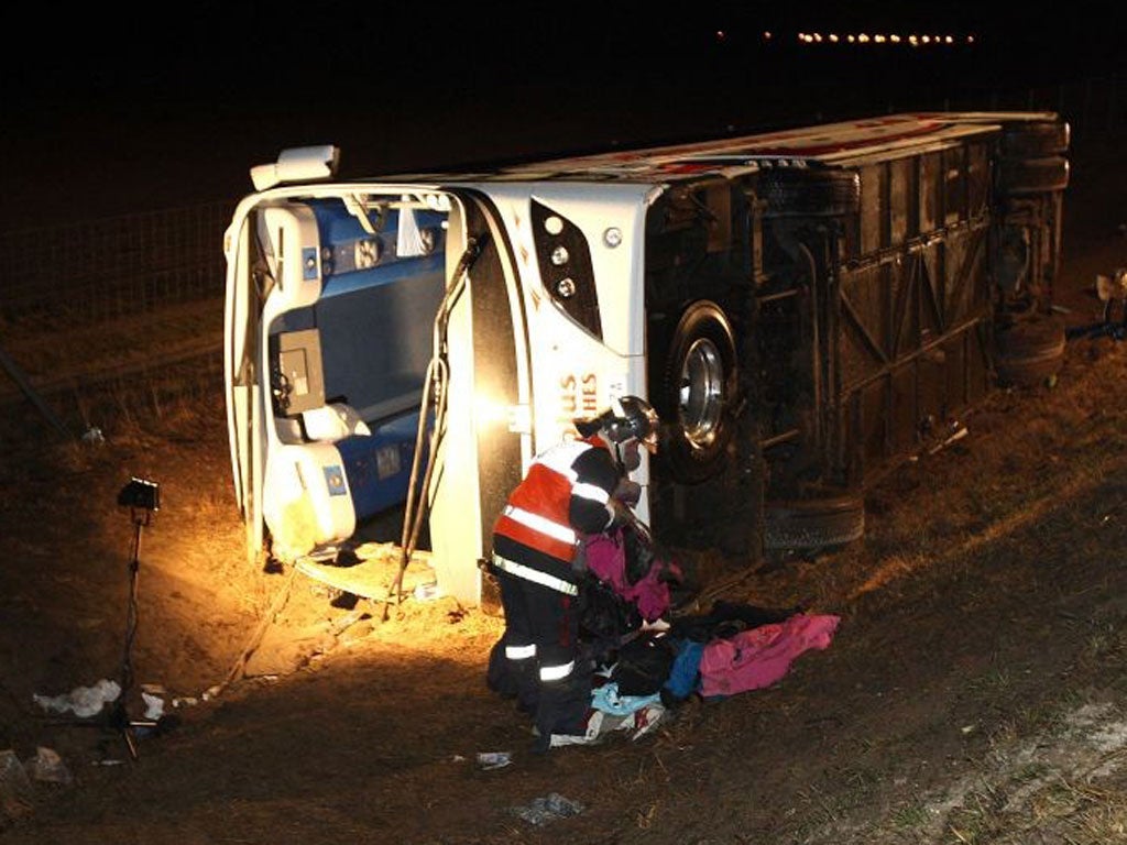 A member of the rescue team works next to the damaged bus which crashed while carrying 47 British people