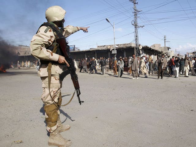 An Afghan anti-riot policeman points to protesters during a demonstration in Jalalabad