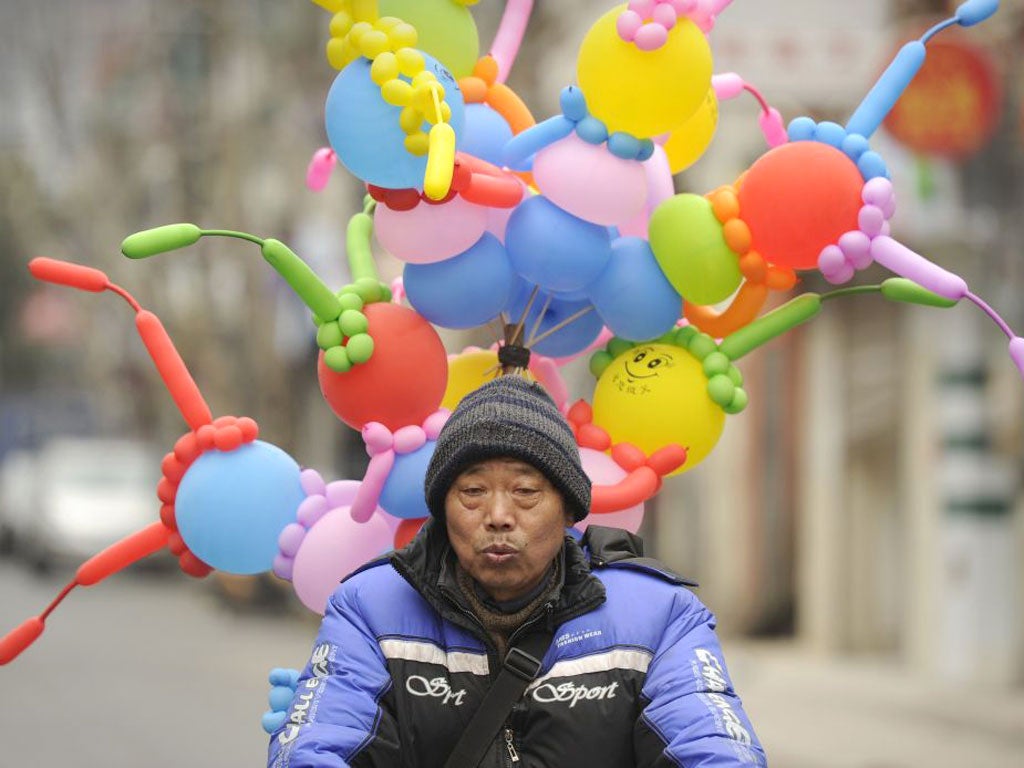 Buoyant economy: A balloon seller cycling in Shanghai