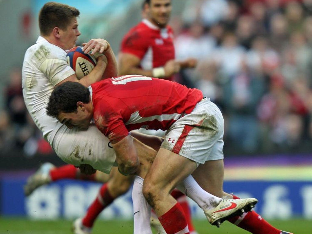 George North of Wales puts in a heavy tackle to drive back the England fly-half, Owen Farrell