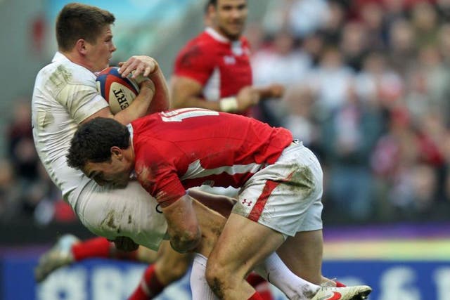 George North of Wales puts in a heavy tackle to drive back the England fly-half, Owen Farrell