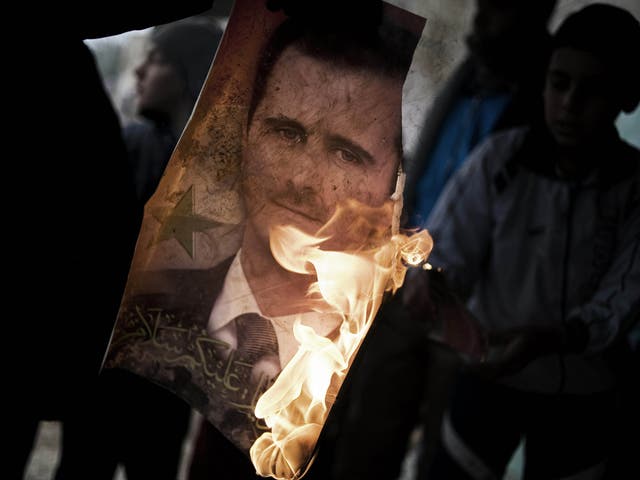 A member of the Free Syrian Army holds a burning portrait of embattled President Bashar al-Assad in Al-Qsair, 25kms southwest of the flashpoint city Homs