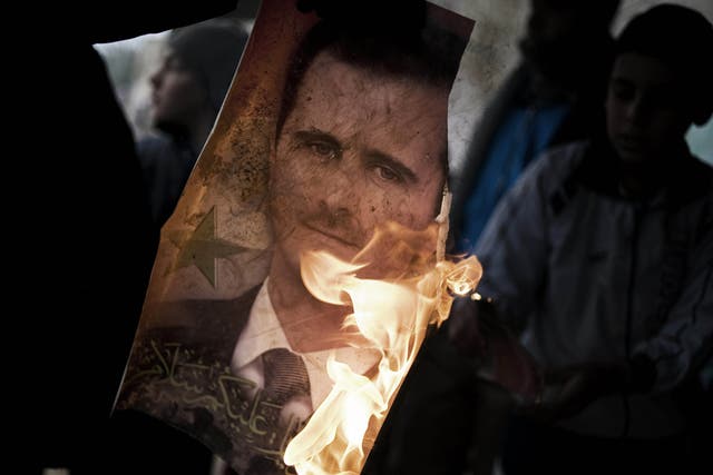 A member of the Free Syrian Army holds a burning portrait of embattled President Bashar al-Assad in Al-Qsair, 25kms southwest of the flashpoint city Homs