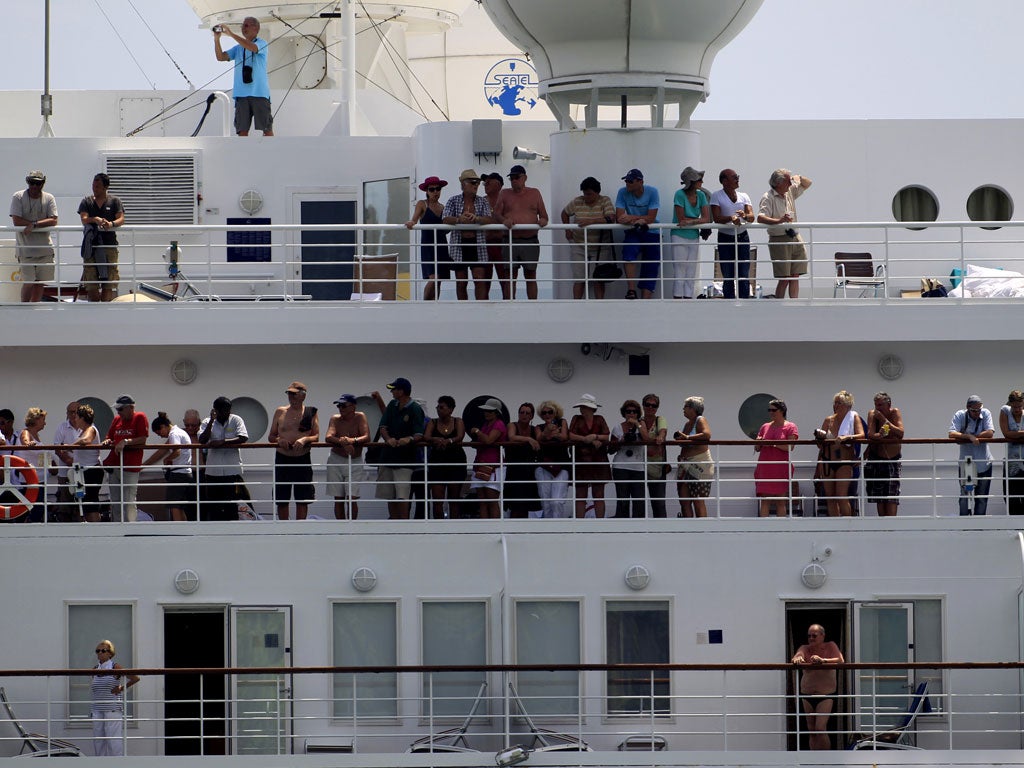 Passengers look out of the Costa Allegra cruise ship as it arrives in the Seychelles