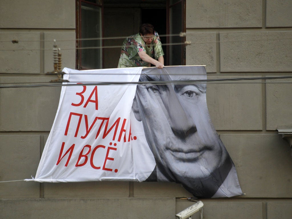 A Russian removes a Putin election poster from an apartment block in Moscow yesterday
