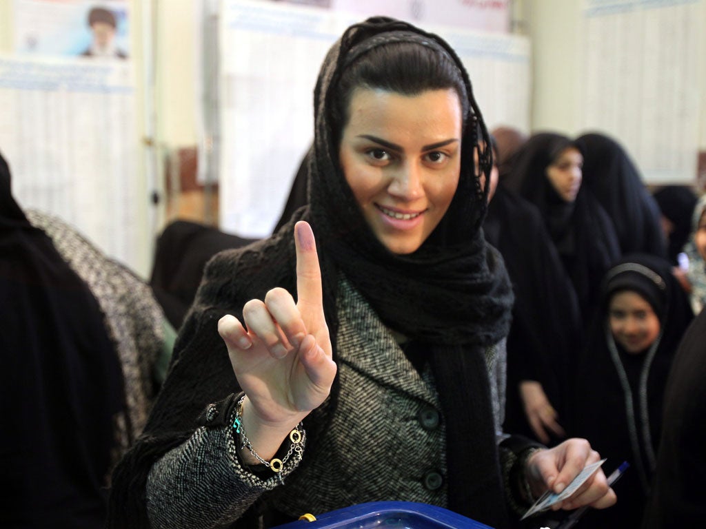 A woman in Tehran shows off the ink print that shows she has voted