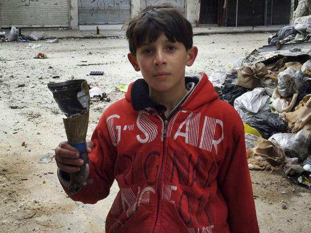 A boy holds the remains of a mortar in Karm Al Zaytoon, a neighbourhood of Homs