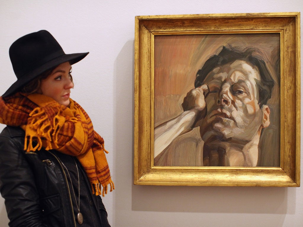 A woman examines the Lucian Freud painting Man's Head (Self Portrait 1) at the National Portrait Gallery exhibition