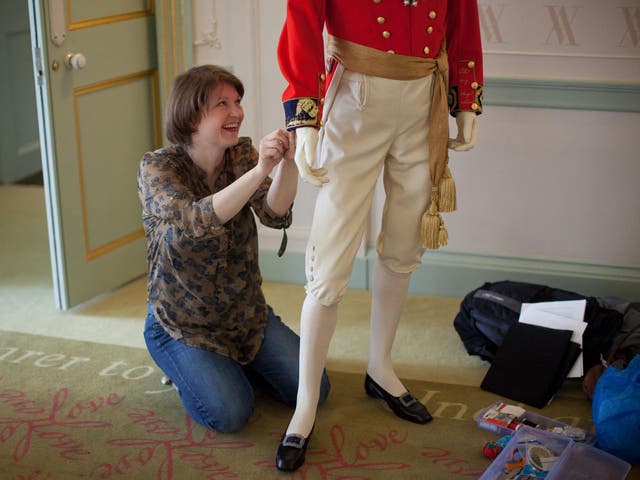 A costume curator works on the replica of the wedding uniform worn by Prince Albert