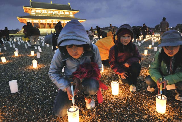 Children light candles during a service near Heijo Palace in Nara, central Japan