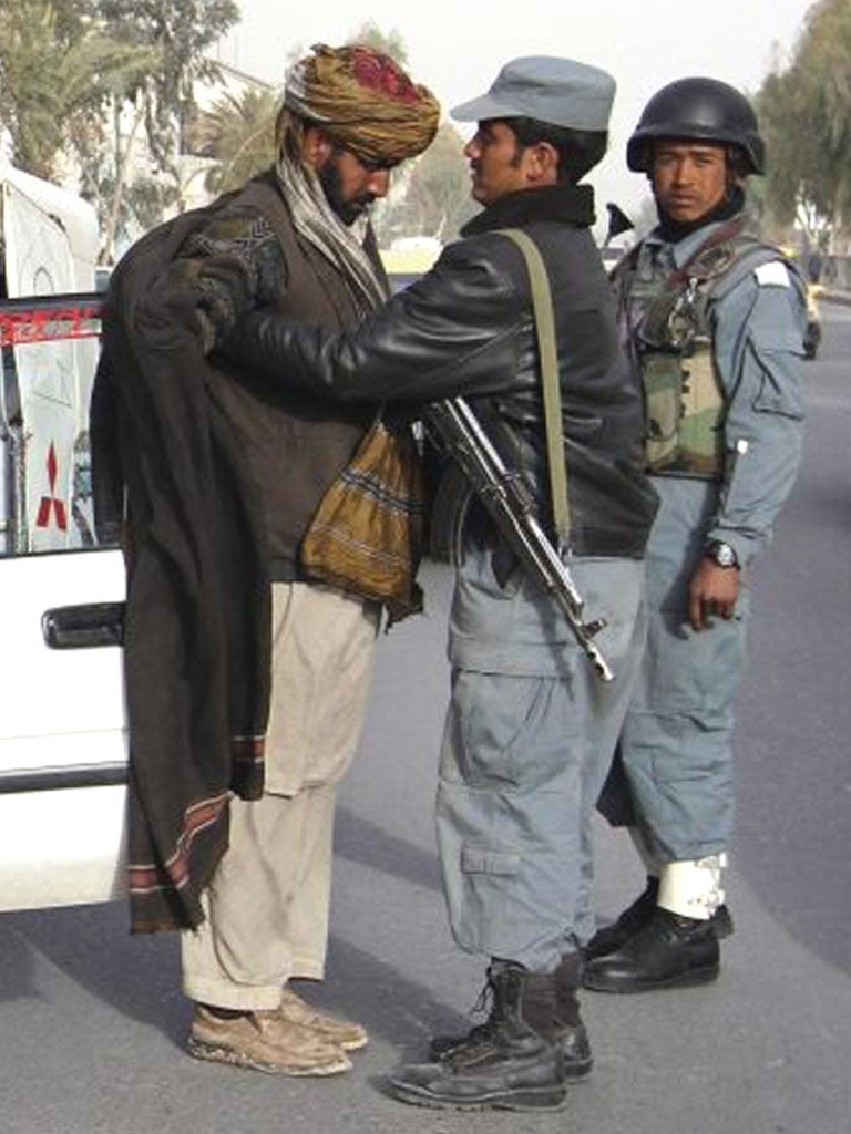 A policeman searches a man at a checkpoint in Kandahar yesterday
