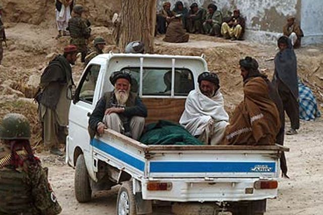 Afghan villagers prepare to remove the victims of Sunday's shooting 