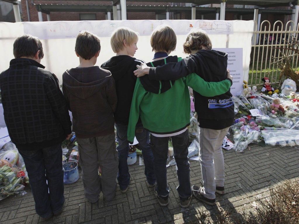 Schoolboys look at floral tributes to the crash victims from Stekske School in Lommel, Belgium, yesterday
