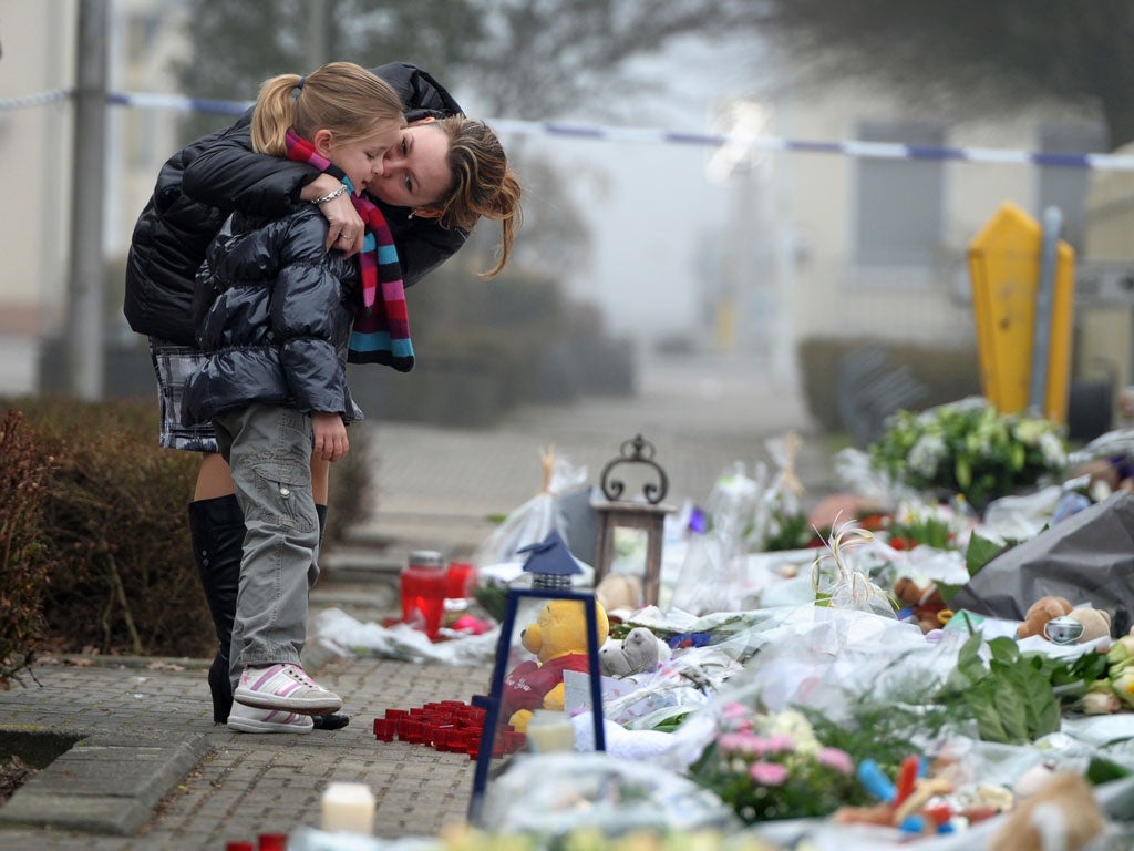 A mother and daughter look at floral tributes at Stekske primary
school