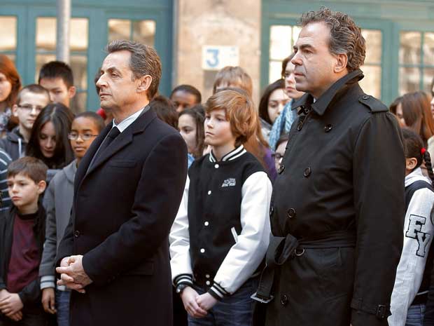 France's President Nicolas Sarkozy (left) and Education Minister Luc Chatel observe a minute of silence with pupils of Francois Couperin secondary school in Paris