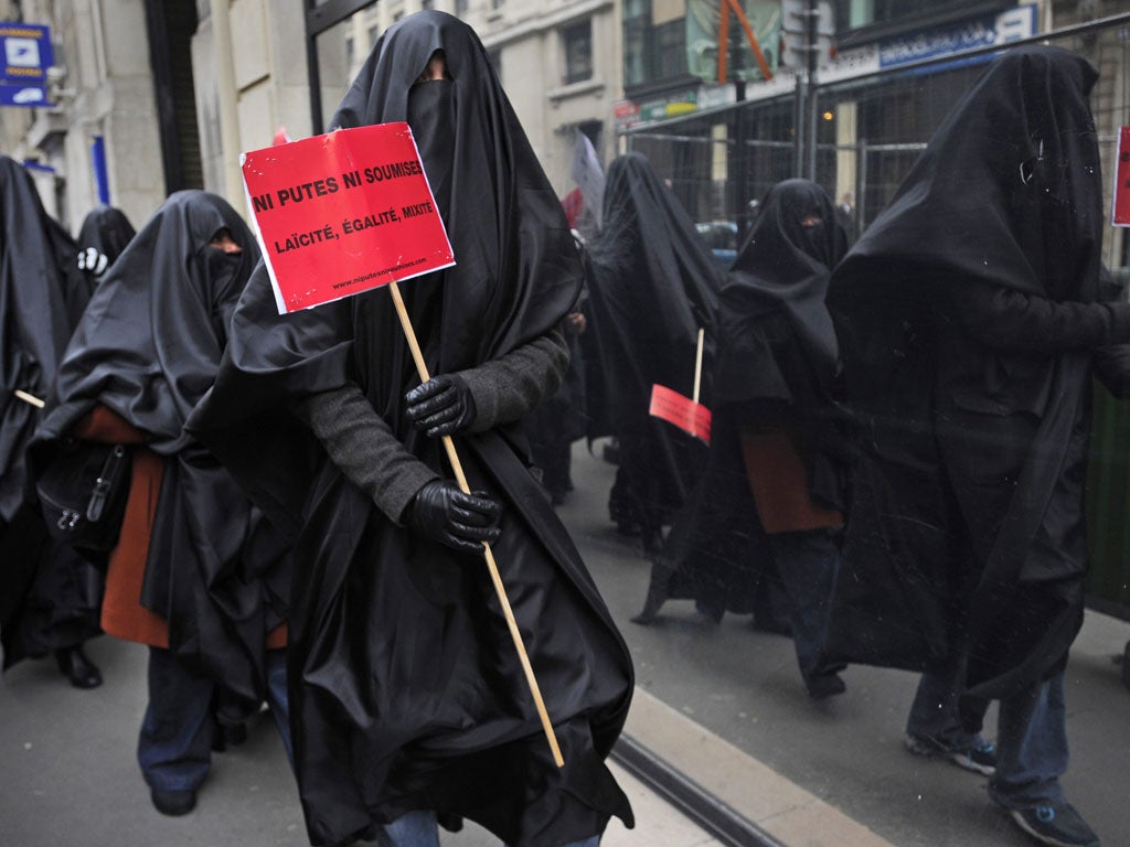A Muslim woman protests in France with a sign that reads 'Neither sluts, nor submissives. Secularism, equality, diversity'