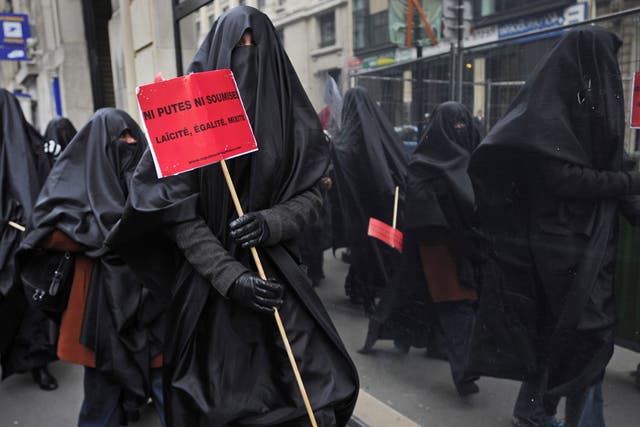 A Muslim woman protests in France with a sign that reads 'Neither sluts, nor submissives. Secularism, equality, diversity'
